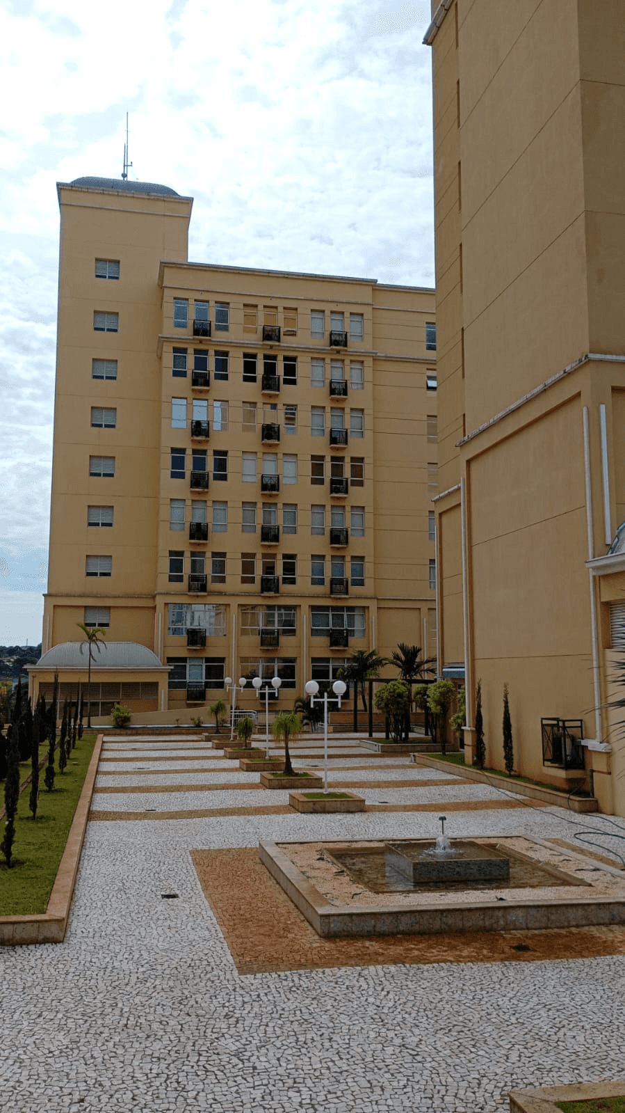 Fachada do prédio do escritório da Altivance: edifício em tons de areia com praça de pedras portuguesas e chafariz à frente